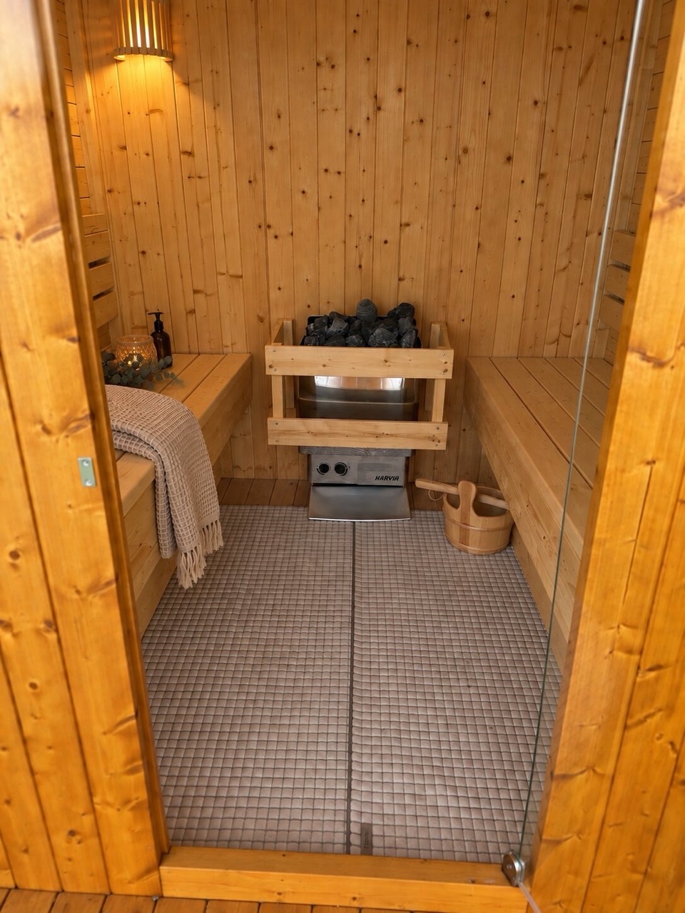 Innenraum der Cube-Sauna mit Holzbänken und Saunaofen